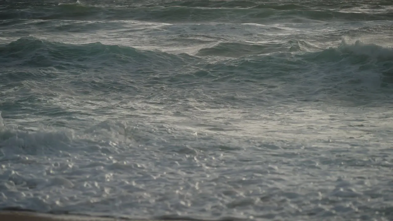 Zooming out of South African waves crashing on beach at sunrise