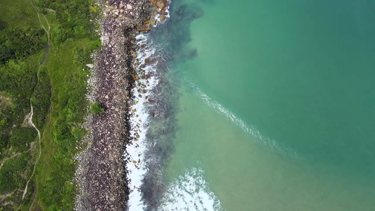 Aerial Top View Drone Footage of Ocean Waves Reaching Green Shore