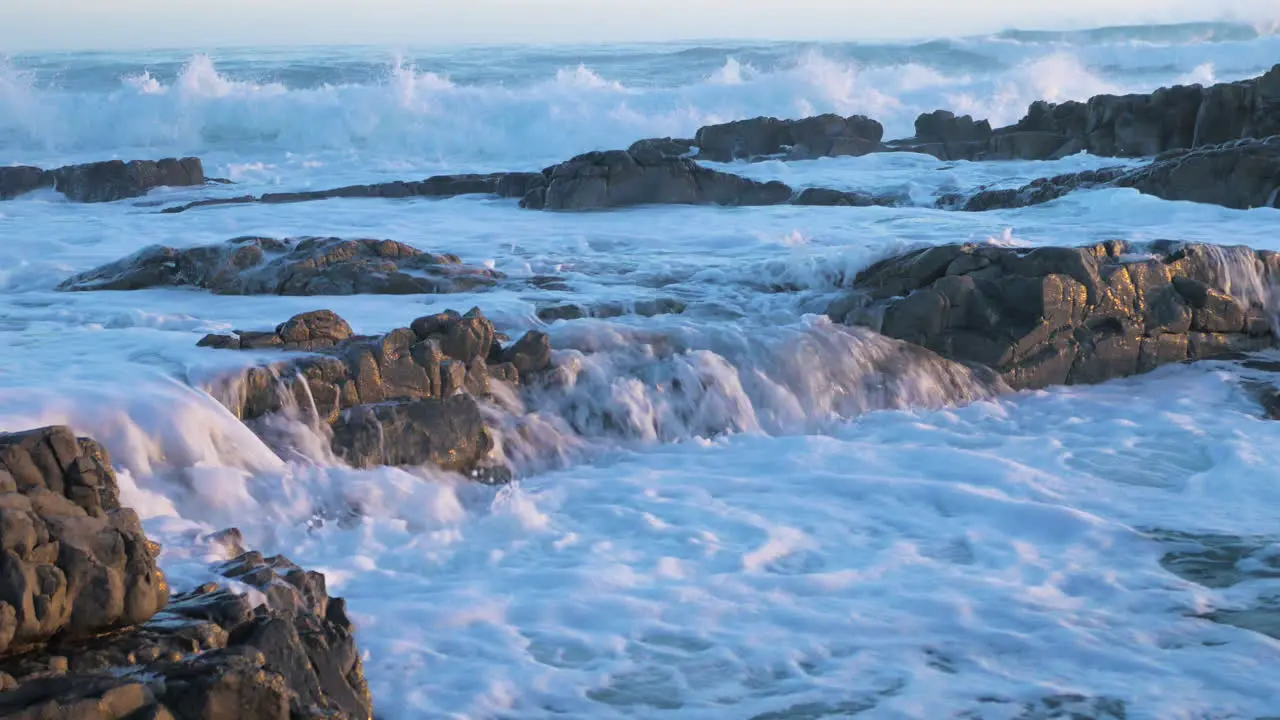 Waves pushing flowing seawater over rocks into another pool close-up