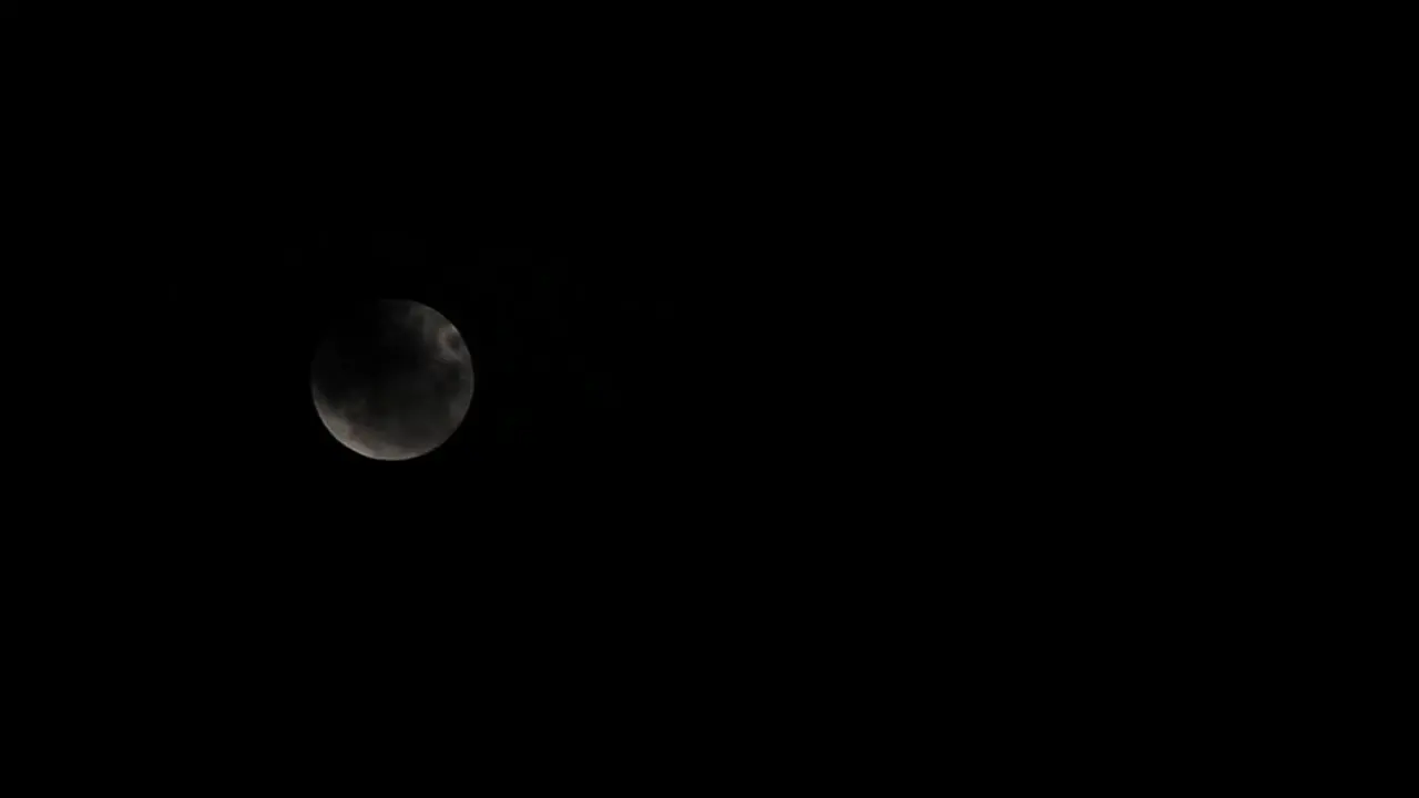 a full moon with some dark clouds passing by