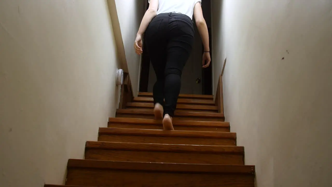 Woman walks up a dark staircase at night