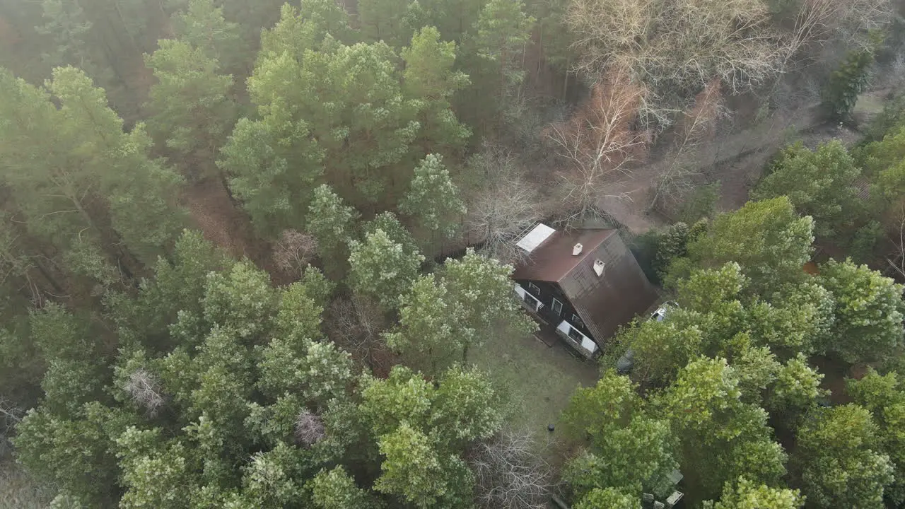 Beautiful aerial shot over remote rural cabin house in dense foggy woods from above