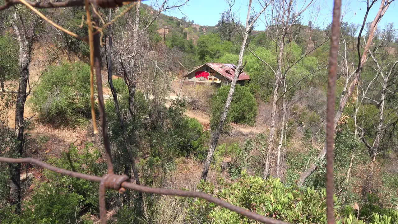 A rundown and scary cabin in the hills is seen from a distance