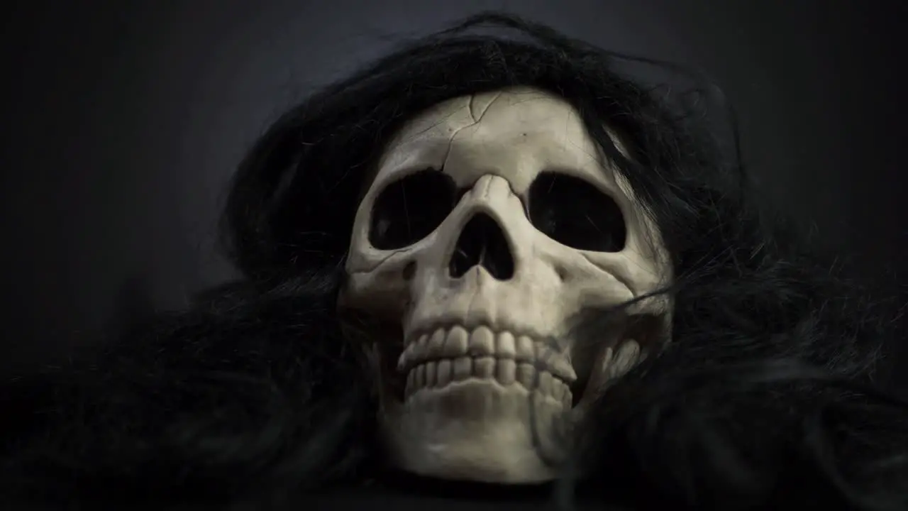 Creepy skull with black hair on dark background medium zoom in shot