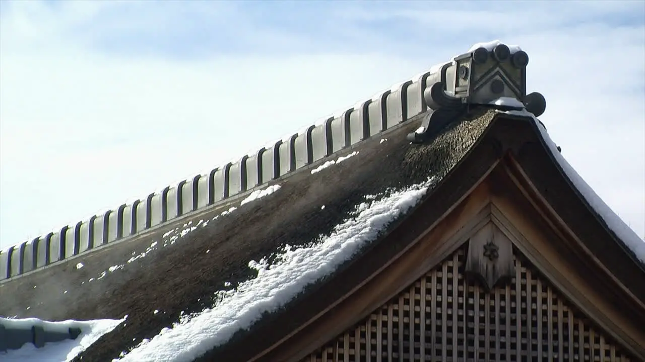 Roof peak of Japanese house with melting snow giving off mist