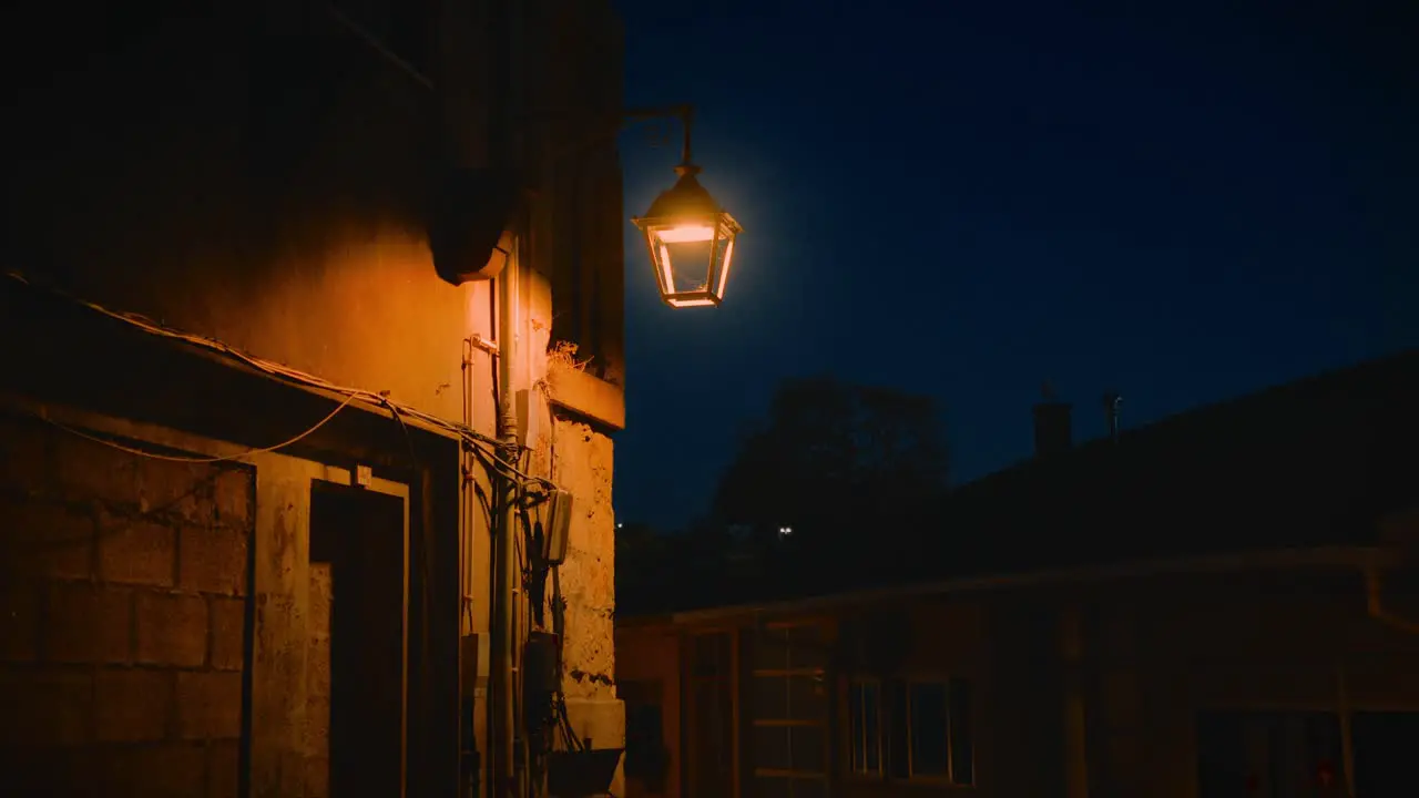 Old Outdoor Lamp Lighting Up Back of Building Sinister Feel Handheld Shot