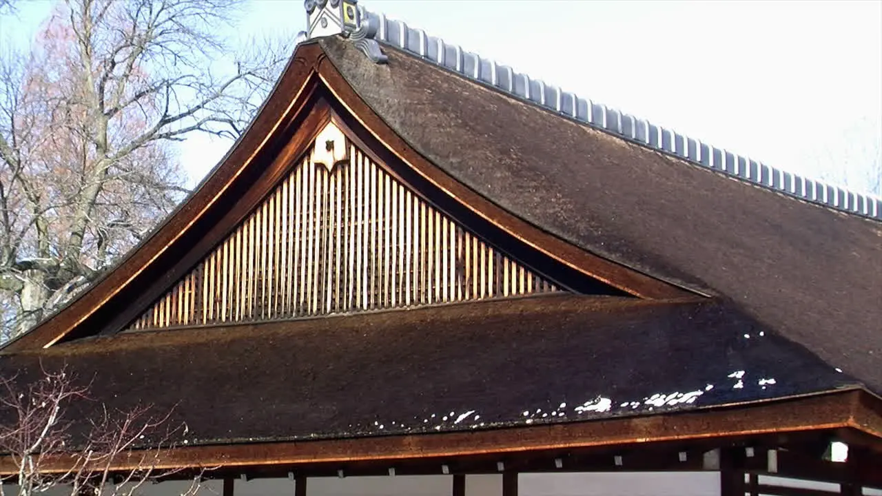 Roof of Japanese house with melting snow emitting swirling mist