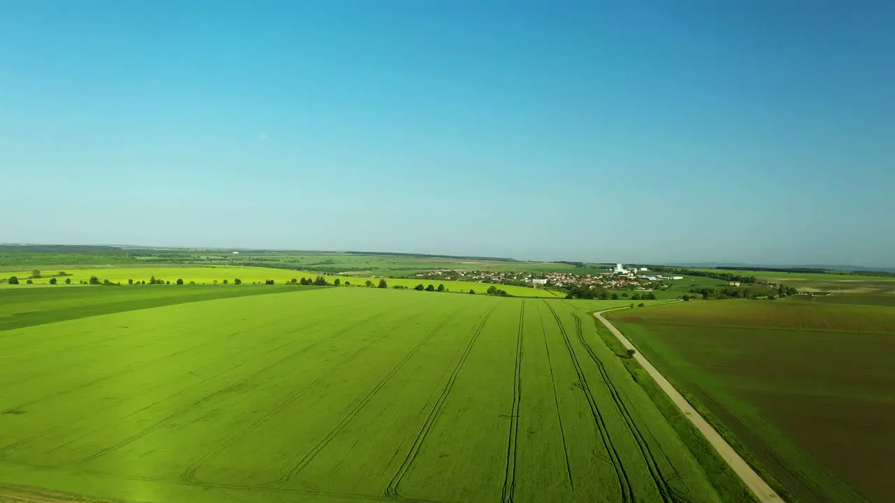 Aerial Footage Over Lush Green Fields With Beautiful Blue Sky New Moon and Small Town in the Distance