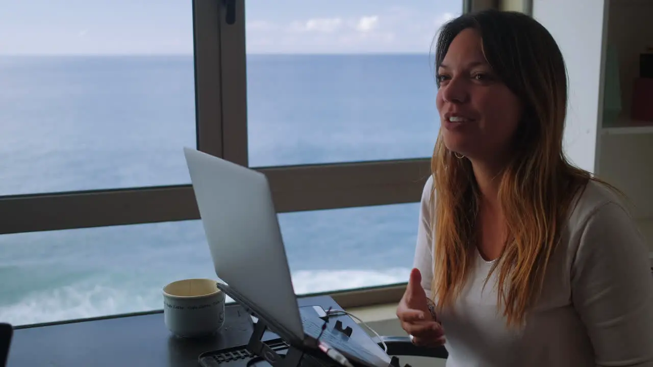 Happy woman telling a story while remote working with a ocean view