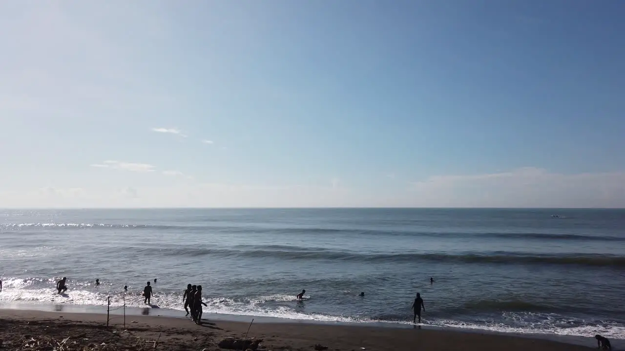 People Swimming and Bathing in the Black Sand Beach Sea Bali Indonesia Ketewel 60 Fps Clear Blue Open Sky Panorama