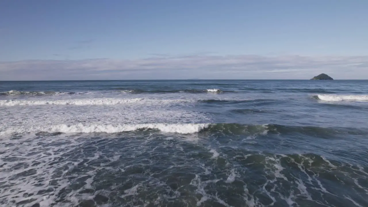 Drone flying towards the ocean an island in the background