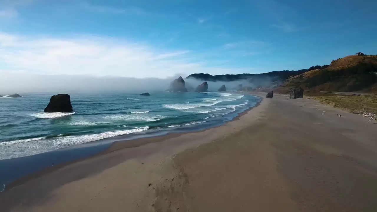 AERIAL Flyover of an Oregon beach as waves crash into the sand