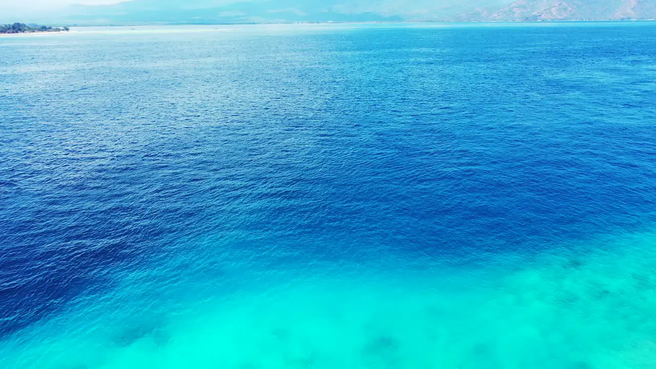 Aerial of the beautiful blue waters waters and a scenic view of mountains on the horizon