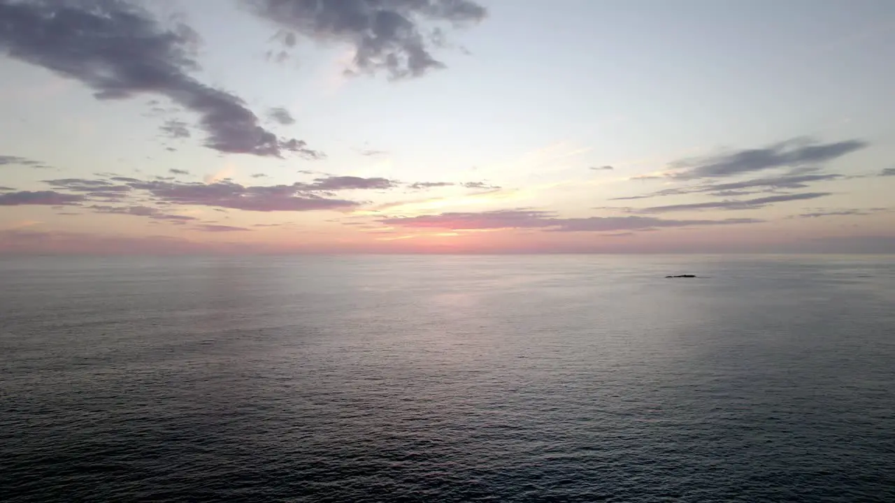 Aerial dolly forward of a vibrant sun setting on the horizon over the ocean