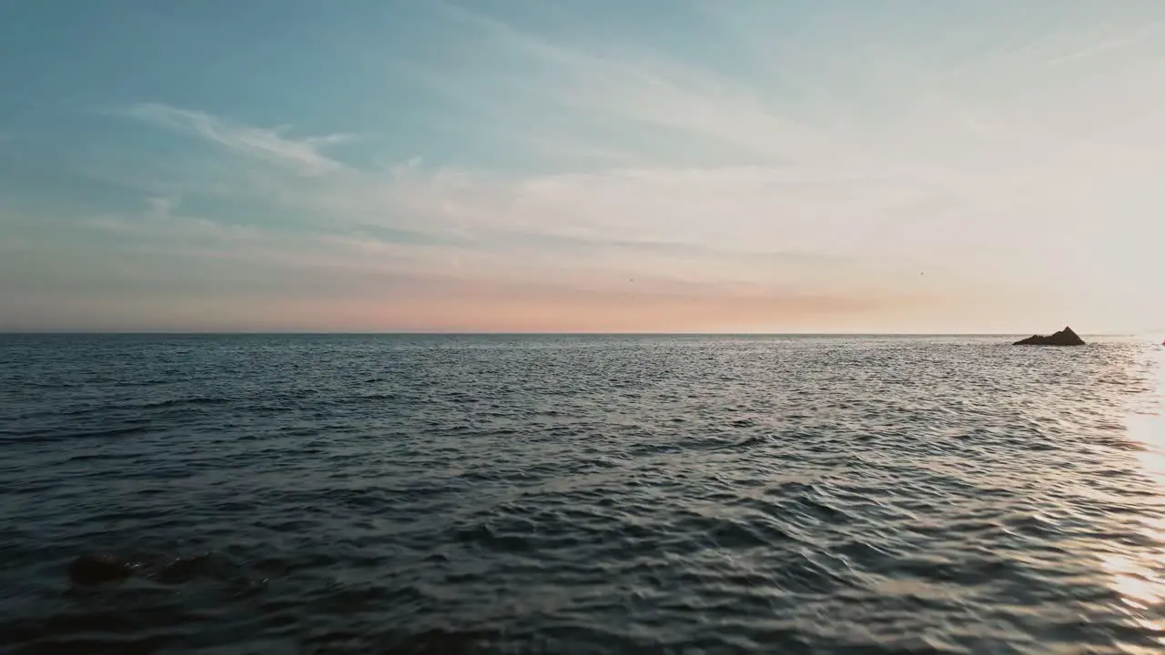 Drone moving fast between the beach rocks at sundown