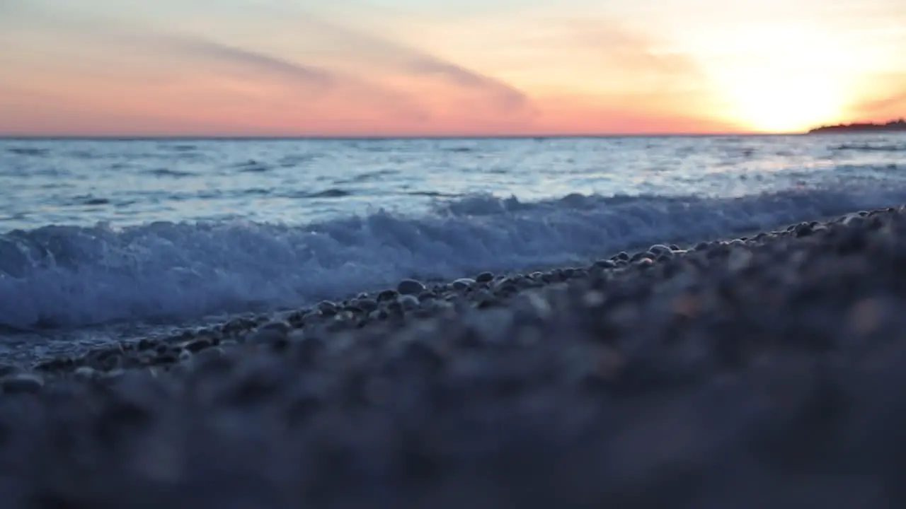 Colorful seascape at twilight with orange sky reflecting on sea surface seen from pebbles beach