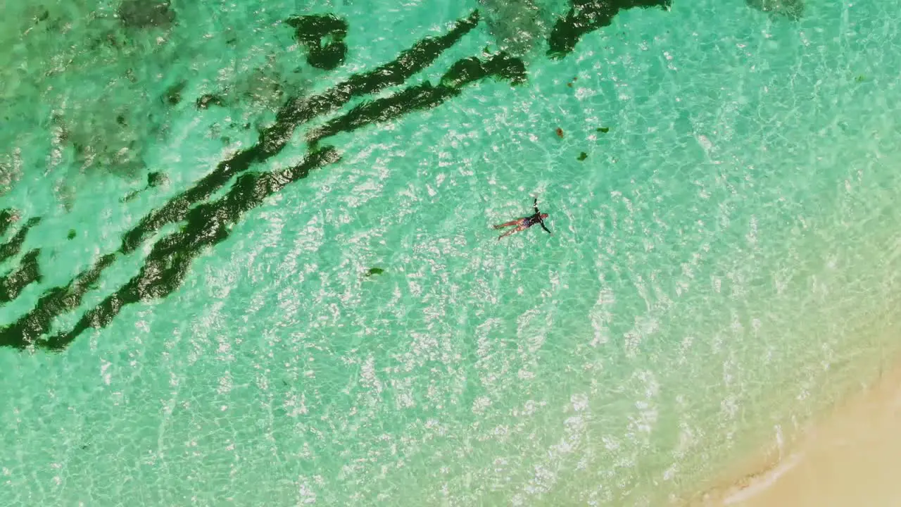 A model floating in a stunning clear water beach in the amazing Caribbean island of Petit St Vincent Grenada