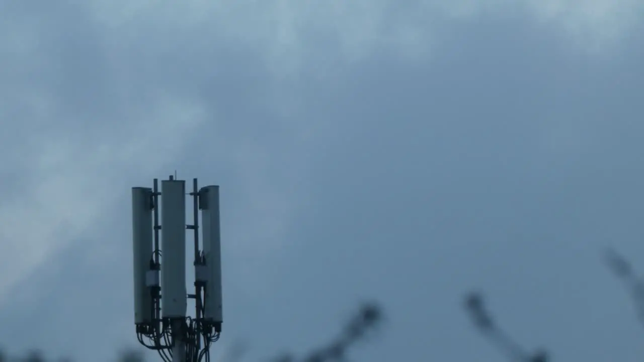 Gloomy cloud passing moon behind cellular telecommunication transmission tower