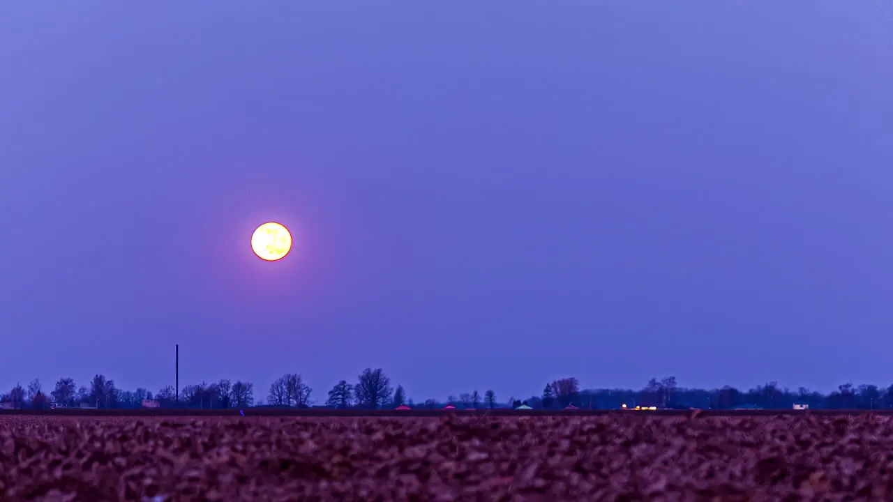 Full moon setting down behind agriculture field fusion time lapse