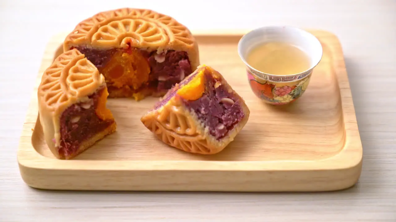 Chinese moon cake purple sweet potato and egg yolk flavour with tea on wood plate