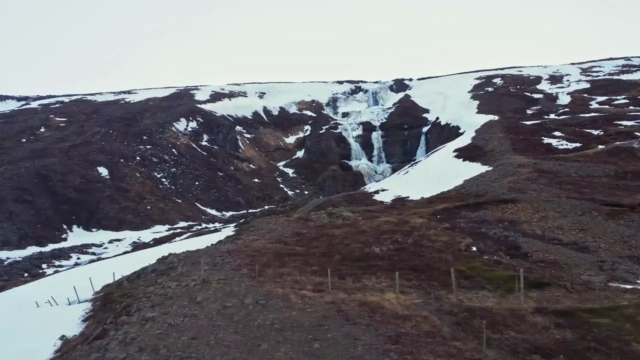 Waterfall on snowy cliff in winter