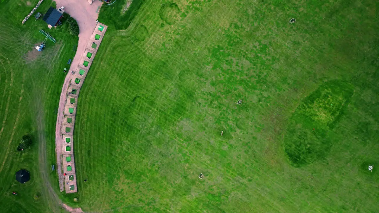 Wide top shot of a golf range with a couple of golfers practicing