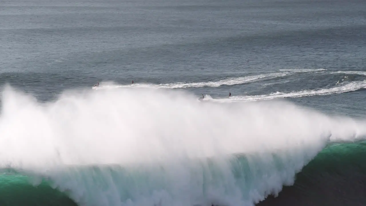 Jet ski drivers pulling surfers onto big wave in Nazare Portugal slow motion