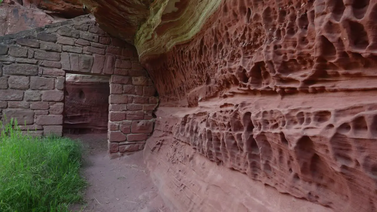 Dolly push in past hole weathered stone rounded grooves to concrete brick doorway cemented into mountain