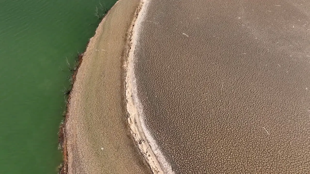 Curved Sau reservoir shoreline contrasting dry arid low drought water terrain and shimmering blue green river Ter