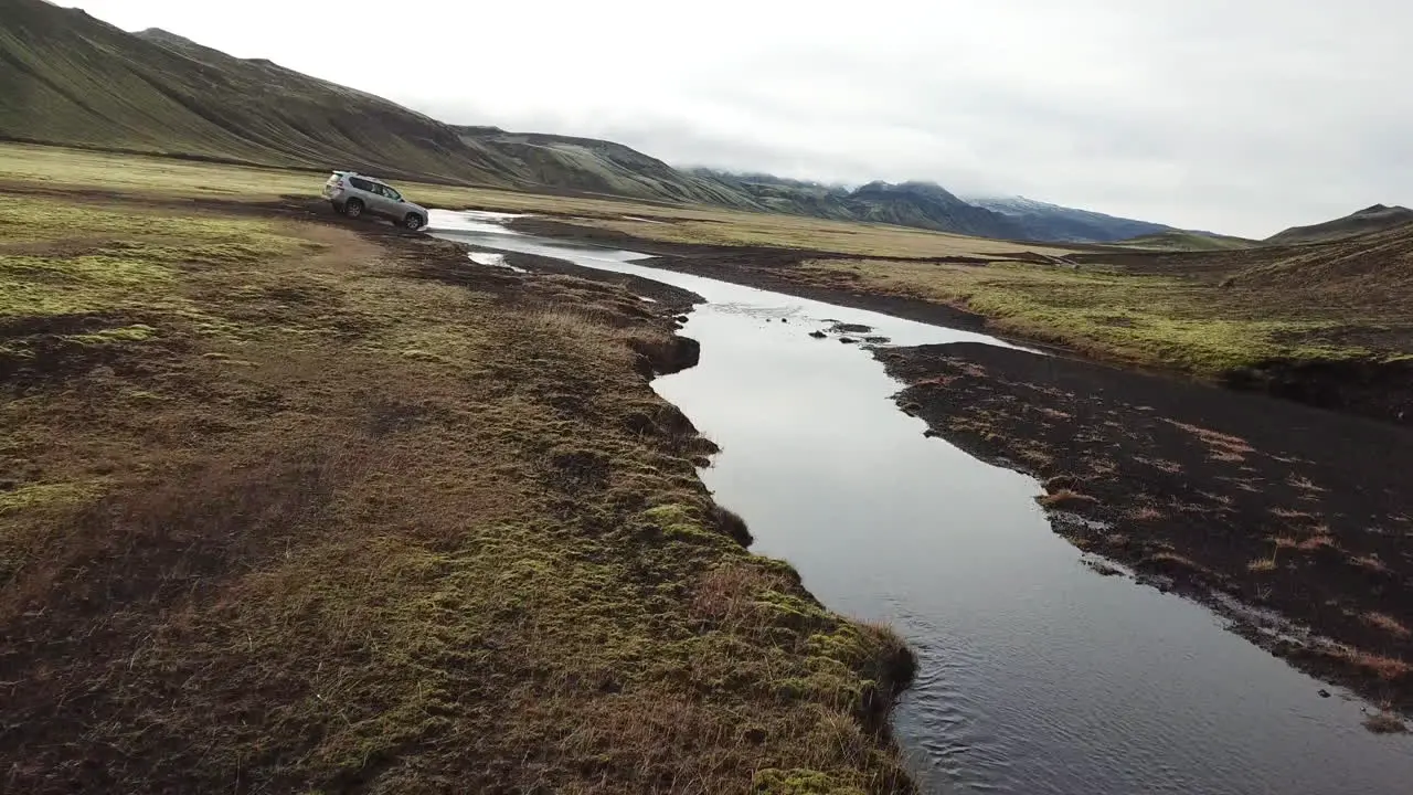 Four Wheel Drive Vehicle Crossing River on Expedition in Iceland Nature Reserve Under Volcanic Hills