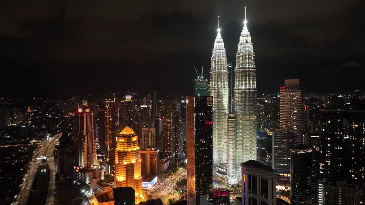 Aerial push in nightime drone shot of Kuala Lumpur and the Petronas Towers