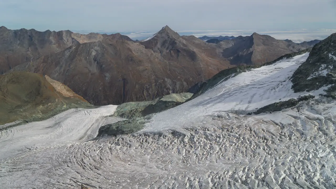 Cinematic time lapse Switzerland Saas Fee ski Resort top of Glacier Gletscher revolving restaurant Swiss partially cloudy afternoon end of summer peak stunning mountain peaks Zermatt matterhorn still