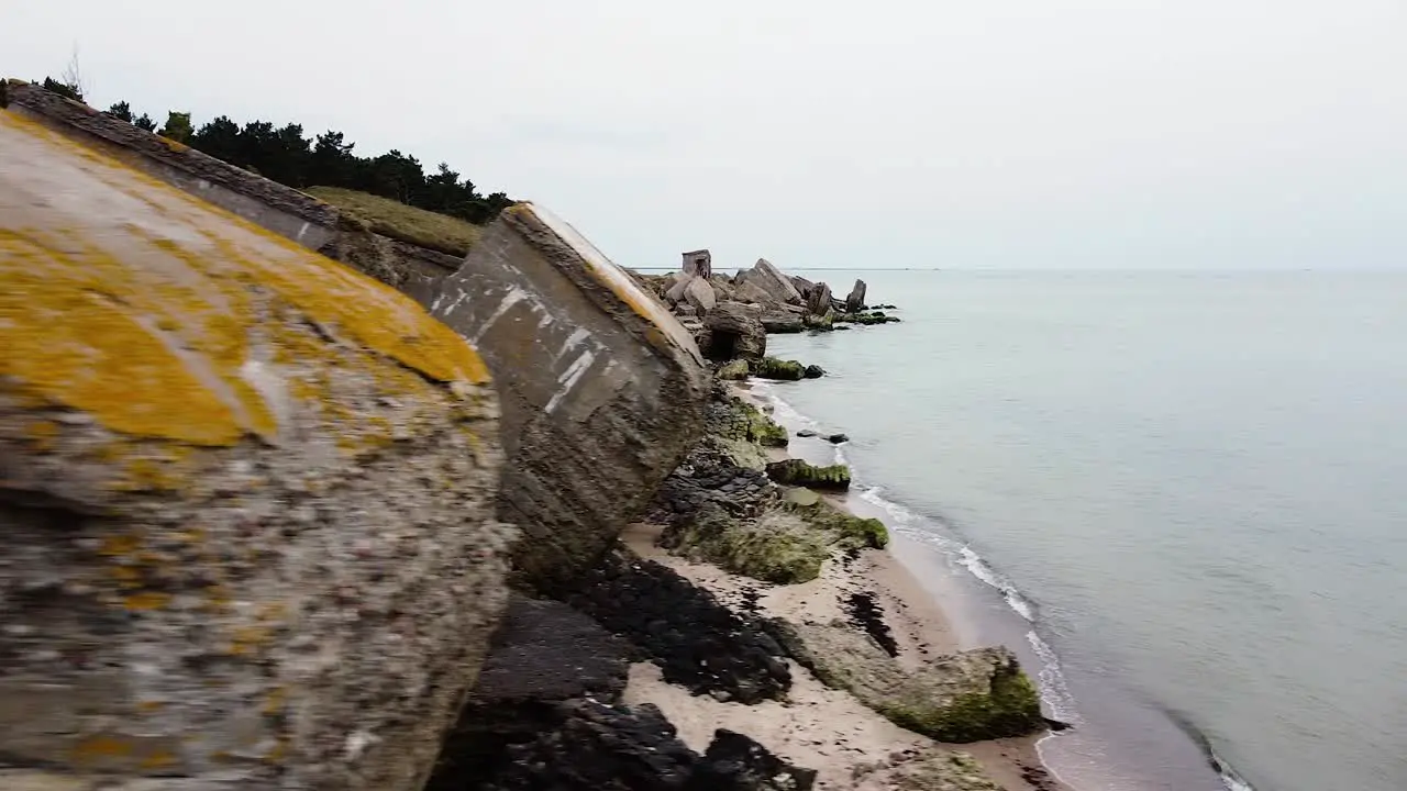 Aerial view of abandoned seaside fortification building at Karosta Northern Forts on the beach of Baltic sea in Liepaja in overcast spring day drone dolly shot moving left