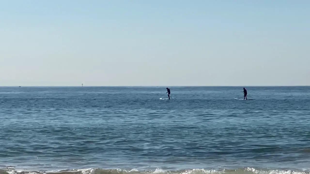 mans paddling on a stand up paddle board in front of the coast of Atlantic ocean