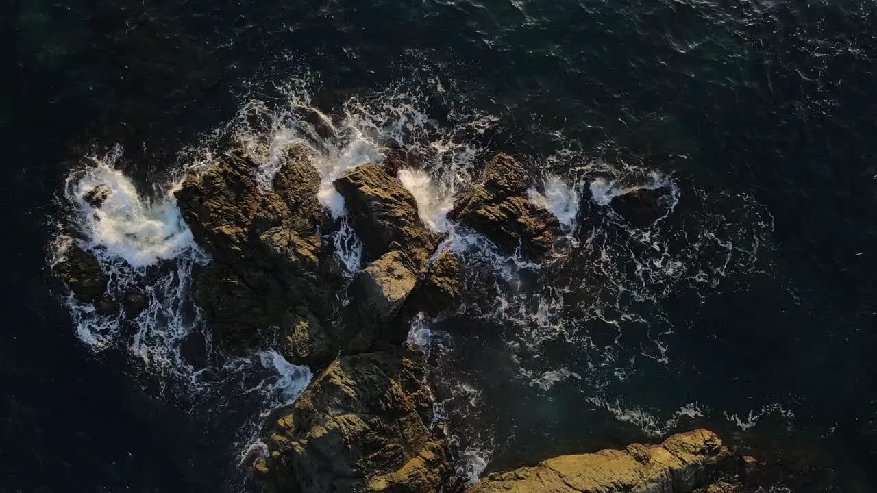 Ocean tide waves slam against rocks during sunset