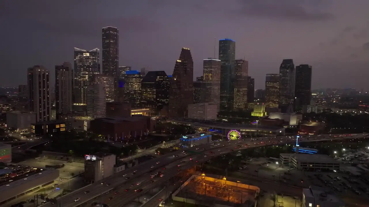 Trucking backwards and pedestaling down drone shot of the Houston skyline at night