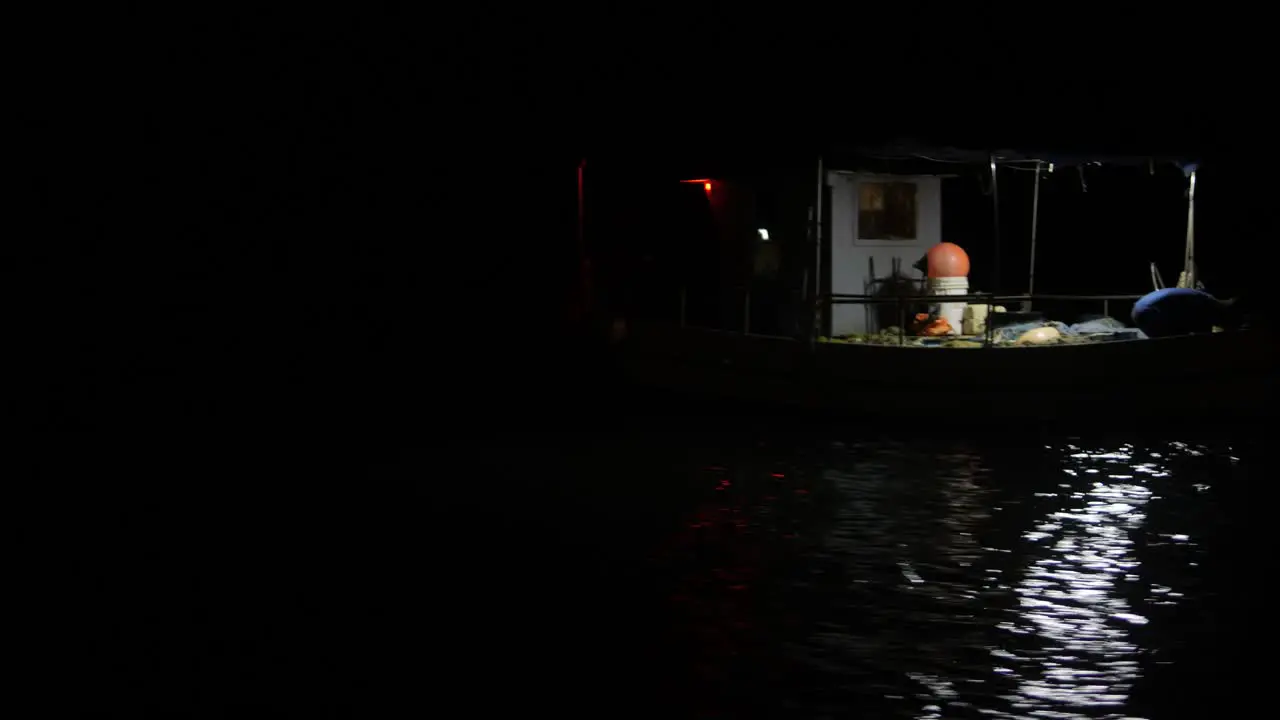 A fisherman gathers his nets from a small fishing boat in the dead of night