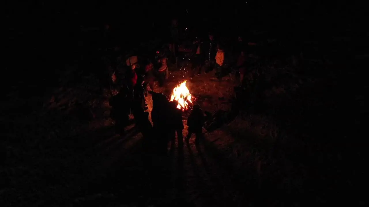 A neat perspective of people standing around a bon fire as seen from a birds eye view