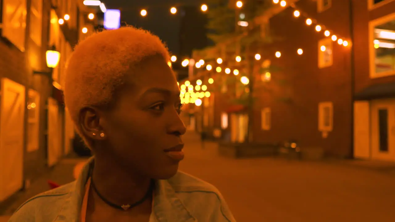 A trendy young woman looking at lights in the street and smiling