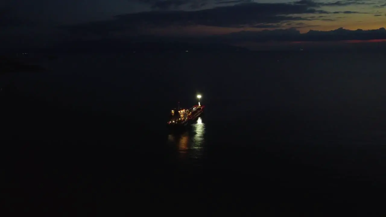 Aerial approaching boat oil tanker parked in sea at night