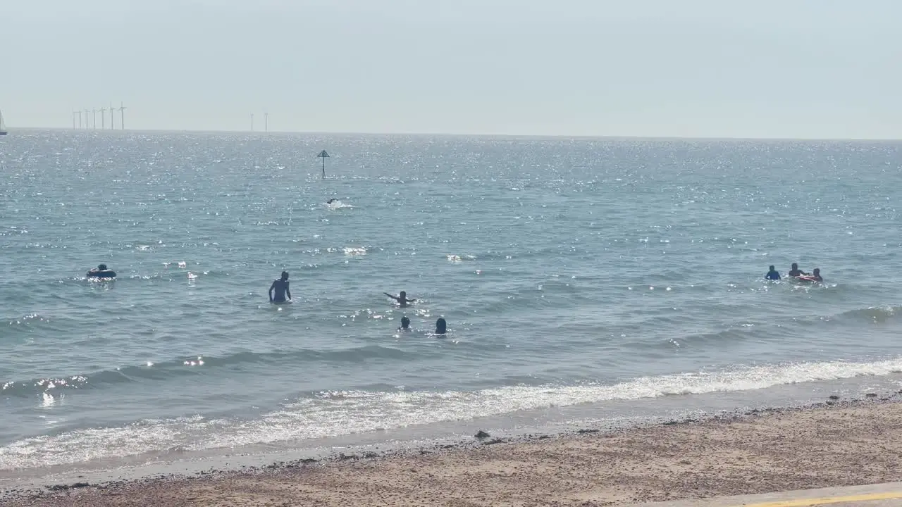 People enjoying the sunny weather at the beach in Clacton on Sea Essex UK