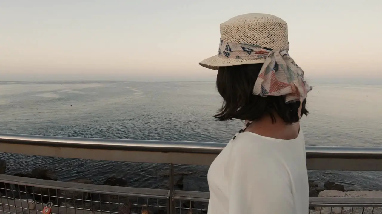 A young girl in her 20s turning around on a dock smiling and sending kisses towards the camera