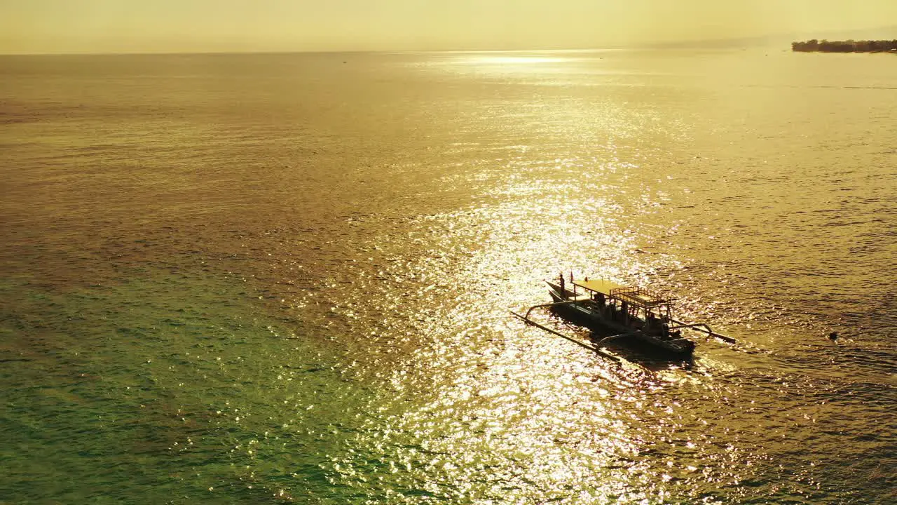 Beautiful golden sunset reflecting in the ripples of the ocean with a small boat sitting on its surface