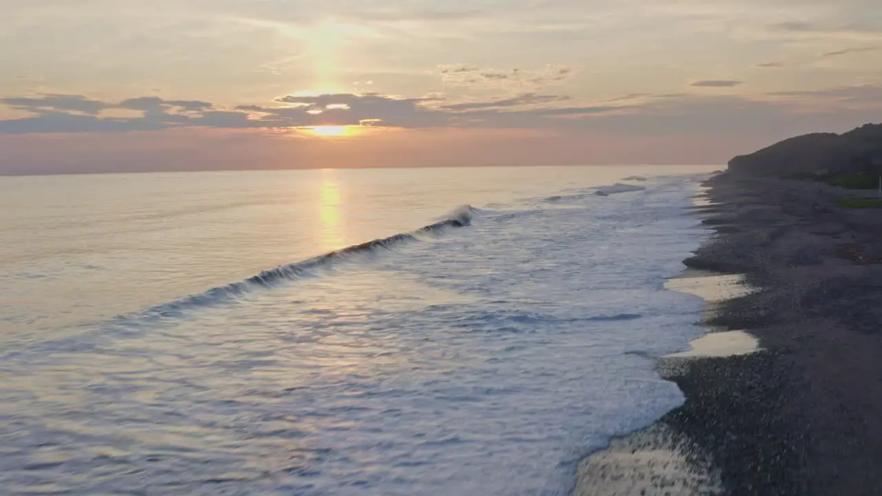 Amazing sunset over beach shoreline waves crashing against pebble beach aerial