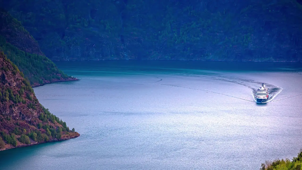 Time lapse shot of cruise ship on fjord between mountains during sunny day aerial wide shot