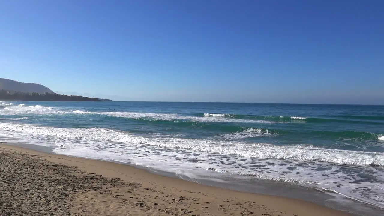 Empty sand beach with ocean and waves in Cefalu Sicily Italy viewed from Lungomare Guiseppe Giiardina street