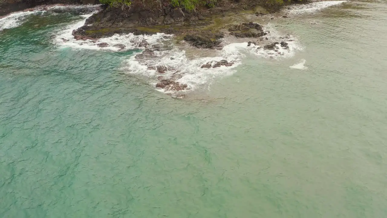 Aerial push in above tropical Panama island palm tree coastline breaking waves on turquoise coral reef