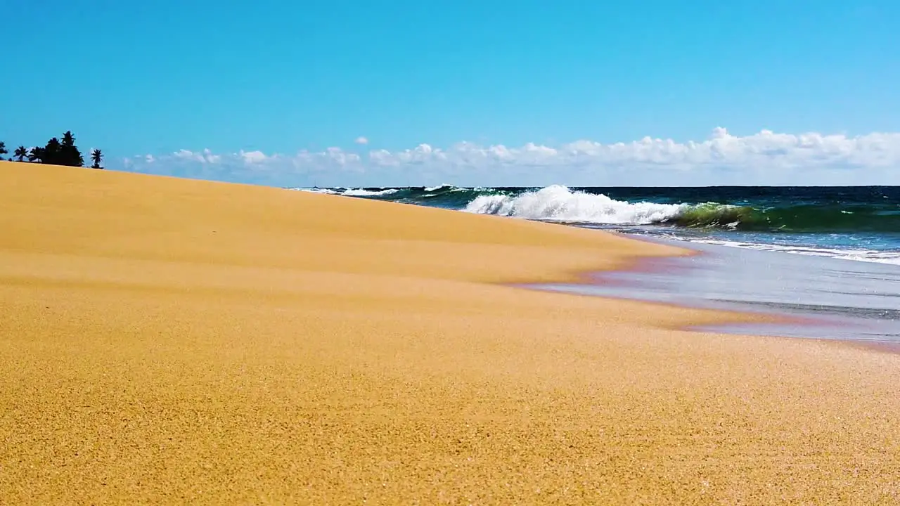 HD Hawaii Kauai slow motion boom up from low shot on the beach to ocean waves crashing and four boats in distance with a layer of clouds on the horizon and blue sky