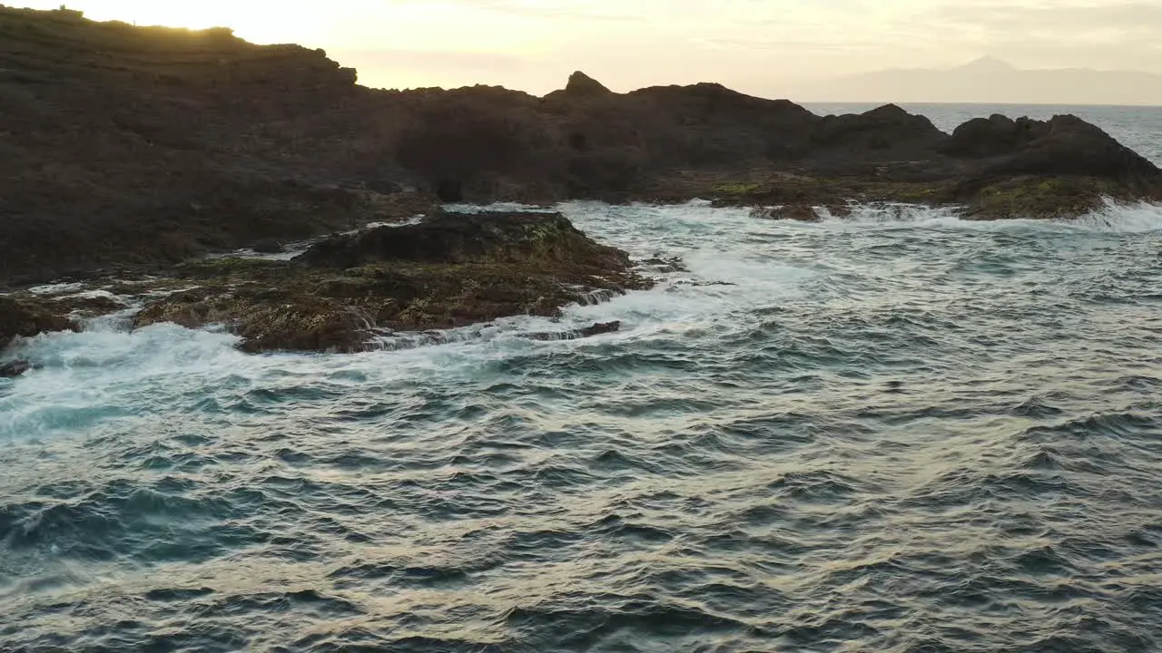 Drone shot of waves splashing on the coast of an ocean