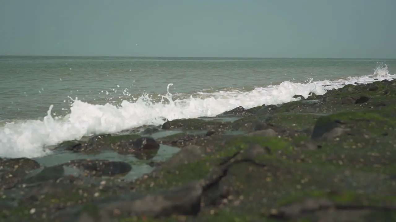 Medium wave hits rocky shore slow motion